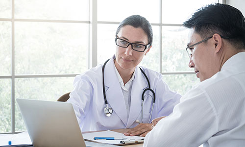 Two providers conversing and looking at laptop